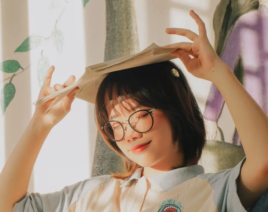 Nữ sinh đeo kính đội sách lên đầu